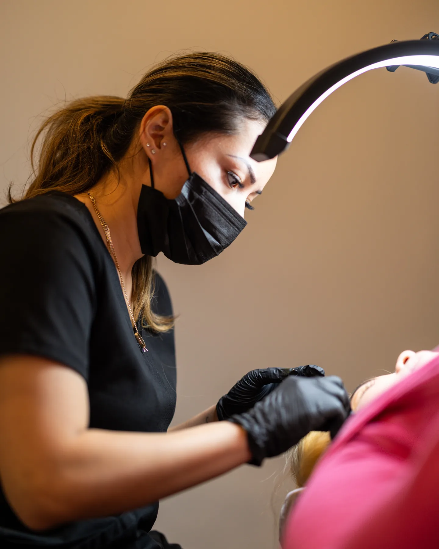 Sheyla, masked, working under a ring light